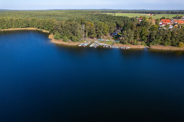 Fototapeta premium Aerial shot of beautiful lake surrounded by forest in a calm autumn day. Germany. 4K video.