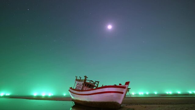Time lapse, nigh start sky with green light from fishing boats. Wooden boat in front