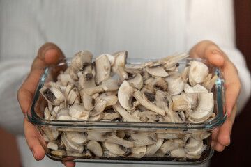 Unrecognizable woman showing into camera frozen food sliced mushrooms champignon homemade. Harvesting concept. Stocking up vegetables for winter storage Healthy food, Cooking ingredients