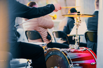 A professional drummer plays a drum kit on a city stage on a sunny day. Big red drum. The moment of...