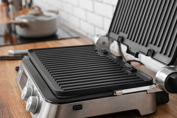 Modern electric grill on table near white brick wall, closeup