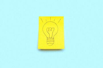Sticky paper with drawn light bulb on blue background. Insight concept