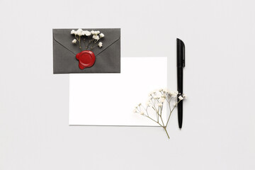 Composition with blank card, envelope, pen and gypsophila flowers on white background