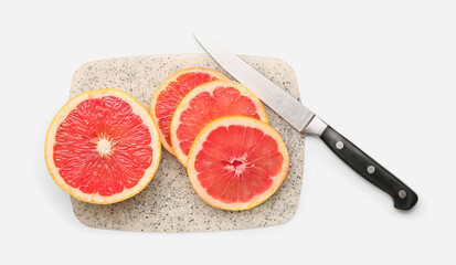 Board with cut grapefruit and knife on white background