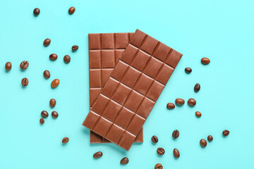 Tasty chocolate bars and coffee beans on color background