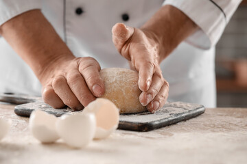 Male chef preparing dough for pasta at table in kitchen, closeup