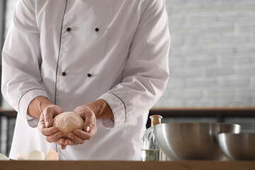 Male chef with raw dough for pasta in kitchen, closeup