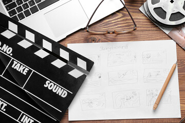 Fototapeta premium Storyboard with movie clapper, laptop and film reel on wooden background