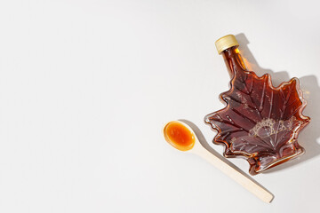 Bottle and spoon of tasty maple syrup on grey background - obrazy, fototapety, plakaty