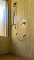 The shower cabin is lined with beige tiles. A metal shower stand, a flexible hose, a soap dish and...