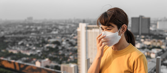 young Asian woman wearing N95 respiratory mask protect and filter pm2.5 or particulate matter against bad Air Pollution in City. Air Quality Index, AQI, Unhealthy, healthcare concept - obrazy, fototapety, plakaty