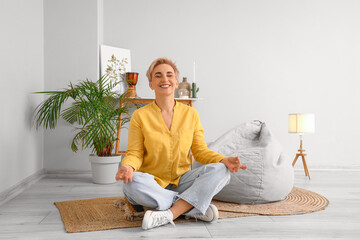 Mature woman meditating at home