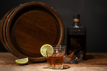 Wooden barrel and glass of cold rum on table