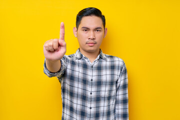 serious angry young Asian man wearing plaid shirt showing stop finger gesture refusing isolated on...