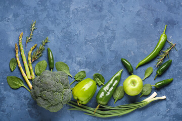 Composition with different fresh green vegetables on blue grunge background