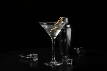 Glass of tasty martini, ice cubes and olives on black background