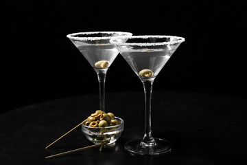 Glasses of tasty martini with olives on black background