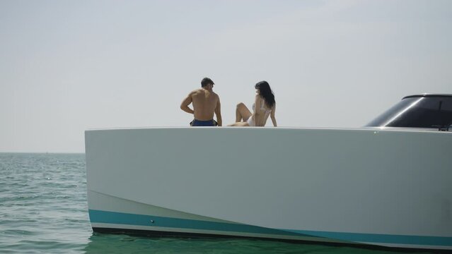 Slow motion rotating shot of a young couple sitting on the edge of a yacht in Dubai