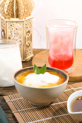 Bubur Sumsum served on wooden table, Javanese dessert porridge of rice flour, coconut milk with brown sugar syrup. A popular iftar food for breaking the fast Ramadan