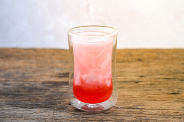 a glass of coconut water with red syrup on a wooden table. Coconut water can prevent vomiting and treat dehydration. Ramadan iftar meal