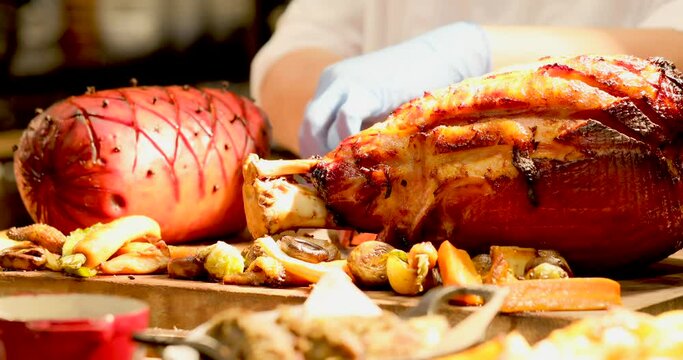 In a buffet restaurant, a male chef slices fresh beef and ingredients for lunch and dinner. Ham, turkey and vegetables on table. Christmas dinner in hotel