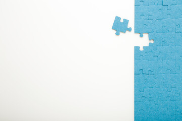Unfinished blue puzzle with last one piece on white table background. Closeup. Empty place for...