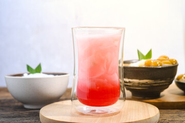 a glass of coconut water with red syrup on a wooden table. Coconut water can prevent vomiting and treat dehydration. Ramadan iftar meal
