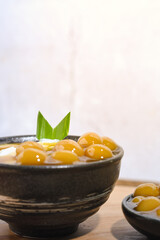 Bubur Sumsum Biji Salak or Candil Ubi served on wooden table, Indonesian traditional dessert porridge of rice flour, coconut milk with brown sugar syrup. Ramadhan iftar food