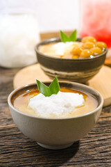 Bubur Sumsum served on wooden table, Javanese dessert porridge of rice flour, coconut milk with brown sugar syrup. A popular iftar food for breaking the fast Ramadan
