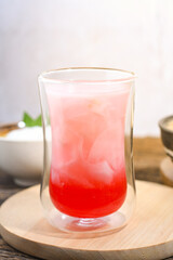 a glass of coconut water with red syrup on a wooden table. Coconut water can prevent vomiting and treat dehydration. Ramadan iftar meal