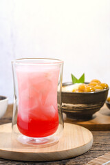 a glass of coconut water with red syrup on a wooden table. Coconut water can prevent vomiting and treat dehydration. Ramadan iftar meal