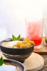 Bubur Sumsum Biji Salak or Candil Ubi served on wooden table, Indonesian traditional dessert porridge of rice flour, coconut milk with brown sugar syrup. Ramadhan iftar food