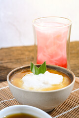 Bubur Sumsum served on wooden table, Javanese dessert porridge of rice flour, coconut milk with brown sugar syrup. A popular iftar food for breaking the fast Ramadan