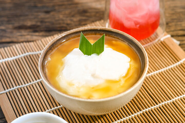 Bubur Sumsum served on wooden table, Javanese dessert porridge of rice flour, coconut milk with brown sugar syrup. A popular iftar food for breaking the fast Ramadan