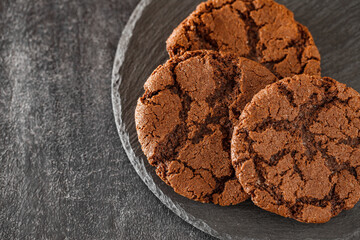 Chocolate oatmeal cookies three pieces on slate stone plate round, dark background, selective focus