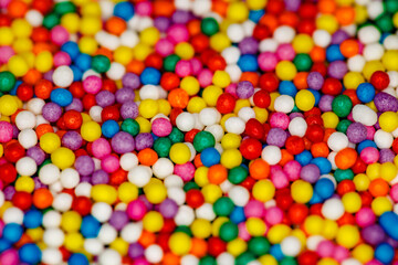 Fototapeta na wymiar Sprinkling close-up for confectionery multi-colored sweet balls, in bulk, red, green, yellow, pink, blue, violet, selective focus