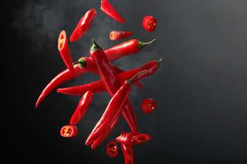 Falling red chili peppers on a black background.