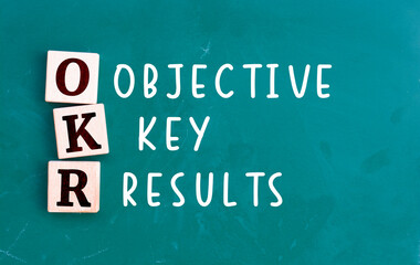 OKR - acronym from wooden cube with letters, Objectives and Key Results OKR concept, chalkboard background
