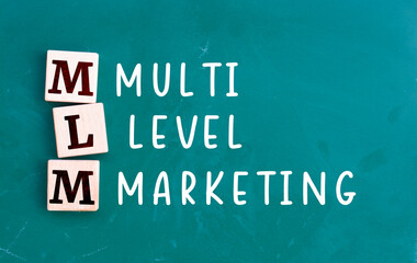 Wooden cubes building word MLM multi level marketing, chalkboard background.
