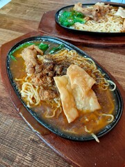 Special chicken noodles sprinkled with black pepper seasoning on a hot plate
