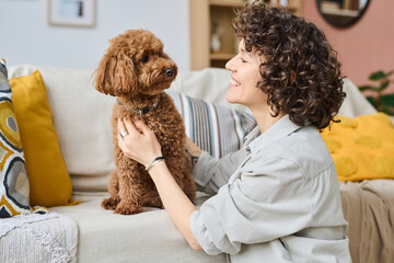 Young woman admiring her little dog while they spending time at home