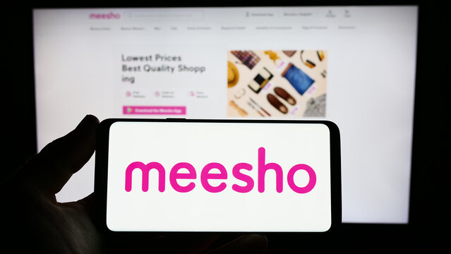 Stuttgart, Germany - 03-26-2023: Person holding smartphone with logo of Indian e-commerce company Meesho on screen in front of website. Focus on phone display.