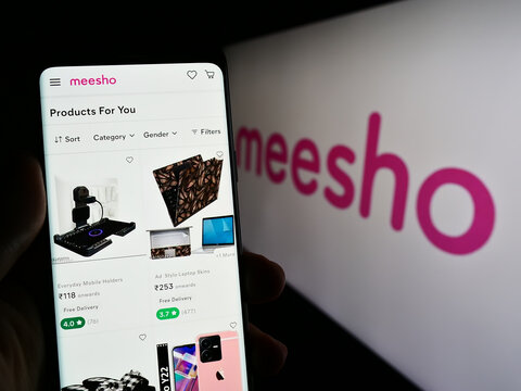 Stuttgart, Germany - 03-26-2023: Person holding cellphone with website of Indian e-commerce company Meesho on screen in front of business logo. Focus on center of phone display.