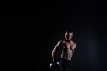 Fototapeta na wymiar Portrait of a happy african man with dumbbells over red and black background