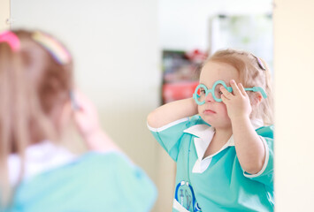 Portrait of a girl with Down syndrome. A girl in a doctor's playsuit. The child plays role-playing...
