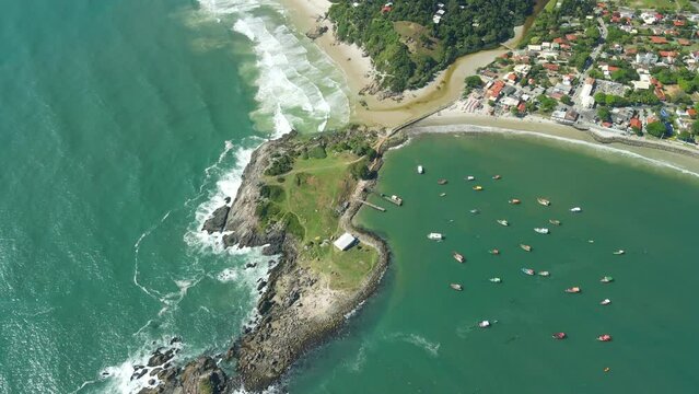 Ocean coastline with rocky island, beach and storm waves in Brazil. Aerial view of Ponta das Campanhas island
