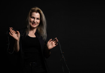 the sexy strict woman with makeup and a fashionable hairstyle poses in studio on black background.