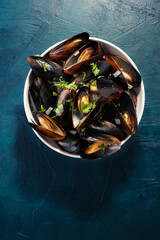 Boiled mussels in bowl with parsley top view