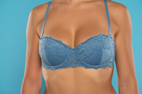 Close up on woman torso. Blue bra and natural breasts cleavage on a blue background