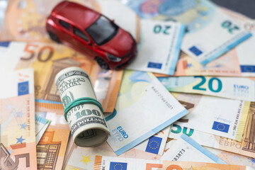 A toy car and car keys in the background of money